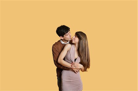 person standing up - Young man hugging girlfriend from behind over colored background Stock Photo - Premium Royalty-Free, Code: 693-06121356