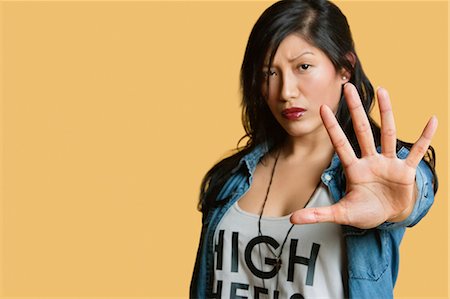 Portrait of a young woman gesturing stop sign over colored background Stock Photo - Premium Royalty-Free, Code: 693-06121361