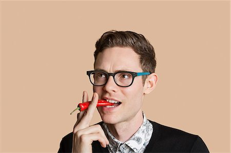 simsearch:693-06324148,k - Mid adult man smoking red chili pepper over colored background Stock Photo - Premium Royalty-Free, Code: 693-06121394