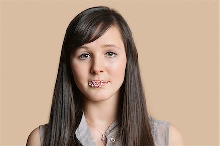 Portrait of a beautiful young woman with sprinkled lips over colored background Stock Photo - Premium Royalty-Free, Code: 693-06121448