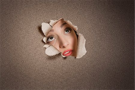 Young Middle eastern woman looking up from ripped paper hole Stock Photo - Premium Royalty-Free, Code: 693-06324086