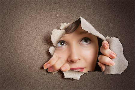 people looking at papers - Young Caucasian woman peeking from ripped paper hole Stock Photo - Premium Royalty-Free, Code: 693-06324092