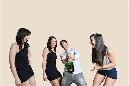 Cheerful young friends with champagne over colored background Stock Photo - Premium Royalty-Free, Code: 693-06324184