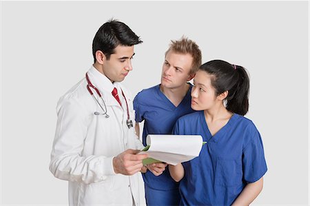 doctor studio - Multi ethnic healthcare professionals discussing medical report over gray background Stock Photo - Premium Royalty-Free, Code: 693-06324234