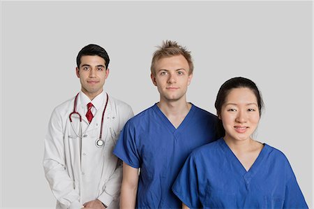 simsearch:693-06324255,k - Portrait of confident multi ethnic medical team standing over gray background Foto de stock - Royalty Free Premium, Número: 693-06324246