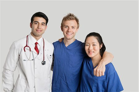 simsearch:693-06324311,k - Portrait of friendly medical team standing over gray background Foto de stock - Sin royalties Premium, Código: 693-06324248