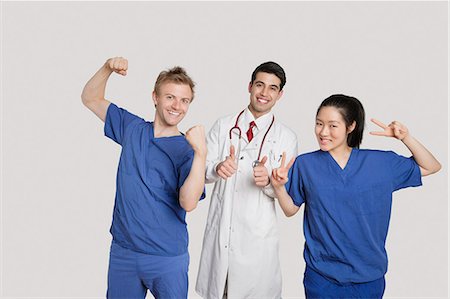 Portrait of a cheerful medical team gesturing over gray background Stock Photo - Premium Royalty-Free, Code: 693-06324240