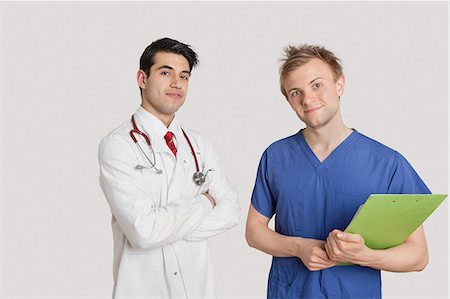 simsearch:693-06324255,k - Portrait of doctor standing with coworker over light gray background Foto de stock - Royalty Free Premium, Número: 693-06324253