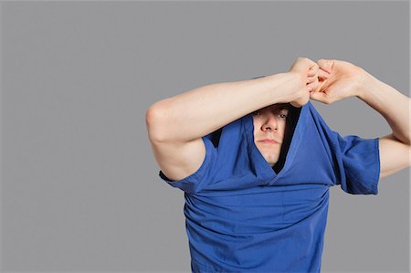 entfernen - Young man removing t-shirt over colored background Foto de stock - Sin royalties Premium, Código: 693-06324286