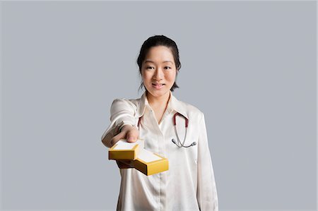 simsearch:693-06324219,k - Portrait d'une jeune femme médecin donnant des boîtes de médecine Photographie de stock - Premium Libres de Droits, Code: 693-06324288