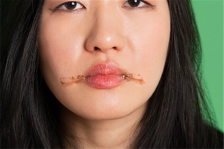 Portrait d'une jeune femme avec des taches de chocolat autour de ses lèvres Photographie de stock - Premium Libres de Droits, Code: 693-06324283