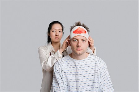 exames de sangue - Portrait of female doctor examining injured male patient Foto de stock - Royalty Free Premium, Número: 693-06324301
