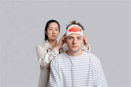 doctor patient portrait - Portrait of female doctor examining injured male patient Stock Photo - Premium Royalty-Free, Code: 693-06324301