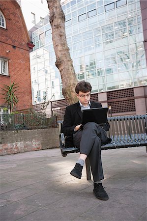 Young businessman working on laptop while sitting on bench Stock Photo - Premium Royalty-Free, Code: 693-06324320
