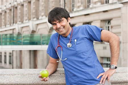 simsearch:693-06324237,k - Portrait of an Indian male doctor holding a green apple Foto de stock - Royalty Free Premium, Número: 693-06324385