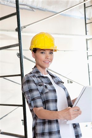 Portrait of beautiful mid adult architect wearing hardhat with blueprints Foto de stock - Sin royalties Premium, Código: 693-06324457