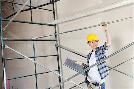 simsearch:693-06324507,k - Beautiful female architect looking away while standing under scaffold Stock Photo - Premium Royalty-Free, Code: 693-06324468