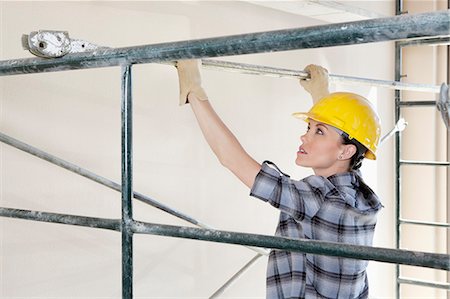 Back view of female contractor placing iron rod on scaffold Foto de stock - Sin royalties Premium, Código: 693-06324469