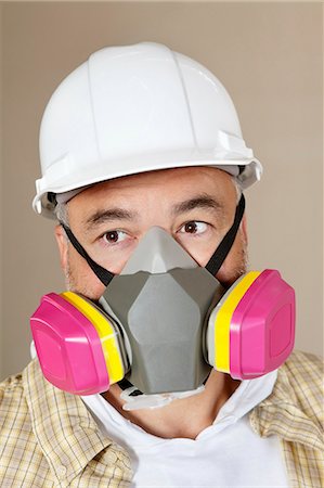 Close-up portrait of contractor with dust mask over colored background Stock Photo - Premium Royalty-Free, Code: 693-06324497