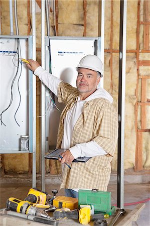 Portrait of a mature male construction worker checking electric meters at construction site Foto de stock - Sin royalties Premium, Código: 693-06324505