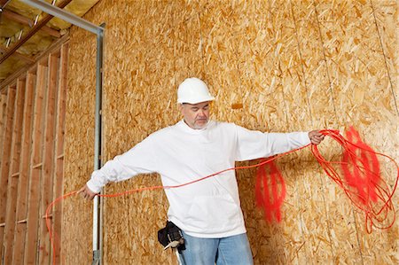 Mature male construction worker with an electrical wire Stock Photo - Premium Royalty-Free, Code: 693-06324512