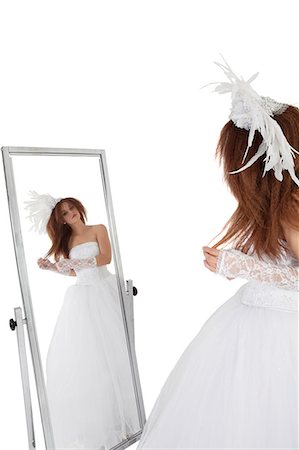 Brunette in wedding gown looking at mirror over white background Stock Photo - Premium Royalty-Free, Code: 693-06324555