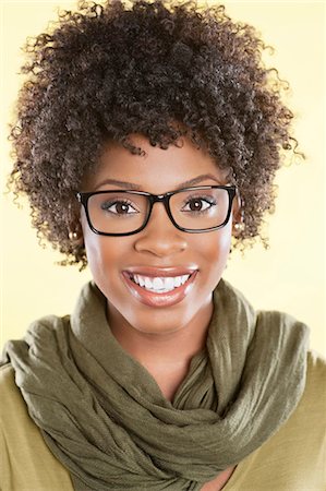 Portrait of a happy African American woman wearing glasses with a stole round her neck over colored background Stock Photo - Premium Royalty-Free, Code: 693-06324604