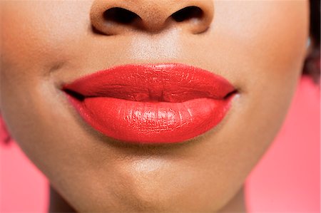 simsearch:693-06324637,k - Close-up view of an African American woman's red lips over colored background Foto de stock - Royalty Free Premium, Número: 693-06324634