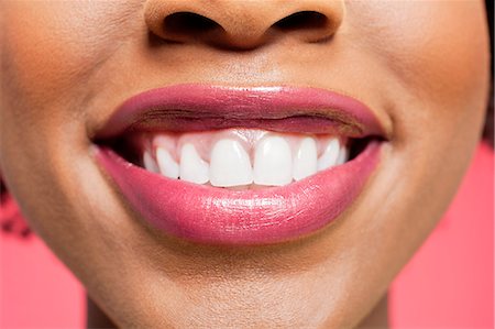 Close-up detail of an African American woman smiling over colored background Stock Photo - Premium Royalty-Free, Code: 693-06324635