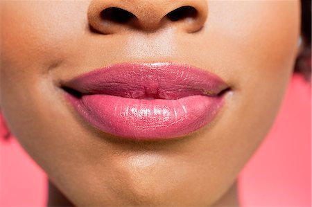 Close-up view of an African American woman's lips over colored background Stock Photo - Premium Royalty-Free, Code: 693-06324633