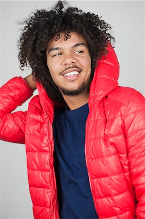 Happy young man wearing hooded jacket while looking away over colored background Stock Photo - Premium Royalty-Free, Code: 693-06324694