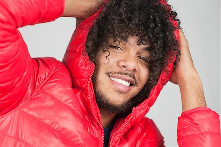 Portrait of a happy curly haired man with hands behind head over colored background Stock Photo - Premium Royalty-Free, Code: 693-06324697