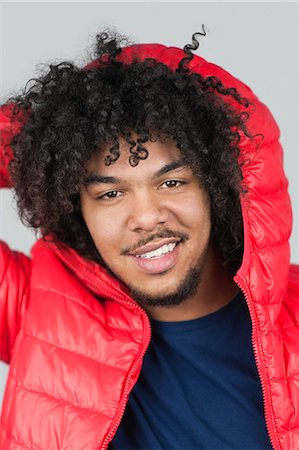 Portrait of a happy young man with hood over colored background Stock Photo - Premium Royalty-Free, Code: 693-06324693