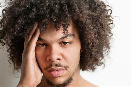 Portrait of young man having headache over white background Stock Photo - Premium Royalty-Free, Code: 693-06324705