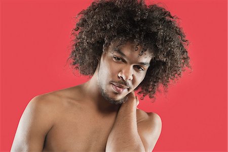 Portrait of a young man with curly hair over colored background Stock Photo - Premium Royalty-Free, Code: 693-06324710