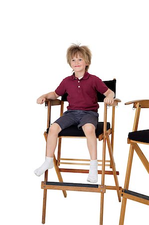 School kid sitting on director's chair over white background Stock Photo - Premium Royalty-Free, Code: 693-06324799