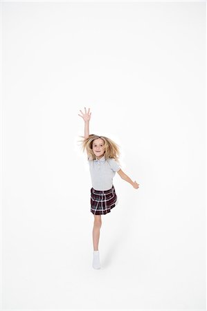 simsearch:693-06324793,k - Portrait of school girl jumping with hand raised over white background Fotografie stock - Premium Royalty-Free, Codice: 693-06324790