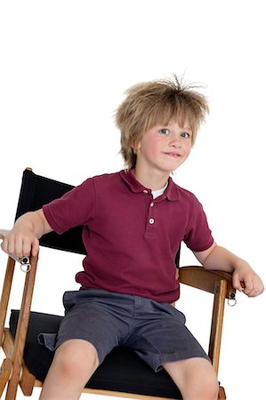 simsearch:693-06324793,k - School boy sitting on director's chair over white background Fotografie stock - Premium Royalty-Free, Codice: 693-06324800