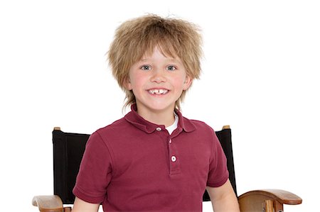 simsearch:693-06324793,k - Portrait of a happy school boy sitting on director's chair over white background Fotografie stock - Premium Royalty-Free, Codice: 693-06324818