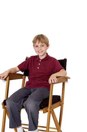 silla de director - Portrait of a happy pre-teen boy sitting on director's chair over white background Foto de stock - Sin royalties Premium, Código: 693-06324813