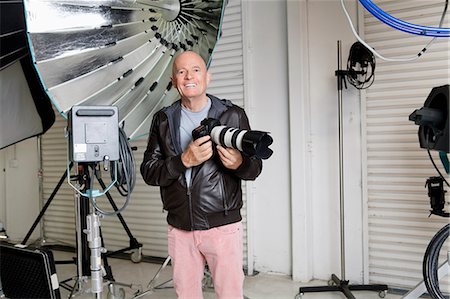 Portrait du photographe senior heureux avec l'appareil photo en studio Photographie de stock - Premium Libres de Droits, Code: 693-06324867