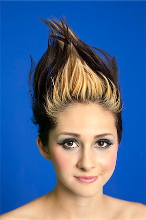 Portrait of a beautiful young woman with spiked hair over colored background Stock Photo - Premium Royalty-Free, Code: 693-06325024