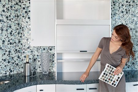 Beautiful young woman with color samples looking at contemporary kitchen cabinets Foto de stock - Sin royalties Premium, Código: 693-06325093