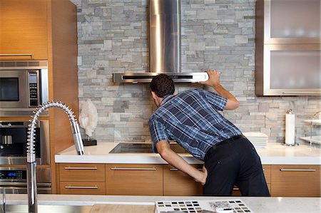 simsearch:693-06323965,k - Back view of young man looking at chimney in model home kitchen Stock Photo - Premium Royalty-Free, Code: 693-06325125