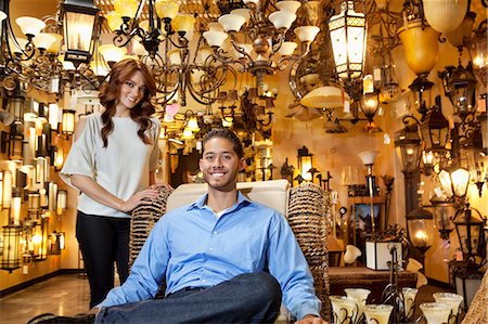 Portrait of handsome young man sitting while woman standing background in lights store Foto de stock - Sin royalties Premium, Código: 693-06325129