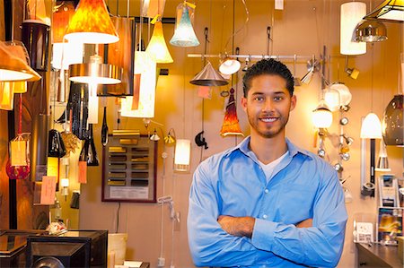 financial happiness - Portrait of a happy young man with arms crossed in lights store Foto de stock - Sin royalties Premium, Código: 693-06325145
