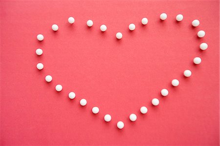 simsearch:693-06325225,k - Close-up of push pins forming heart shaped over pink foreground Foto de stock - Sin royalties Premium, Código: 693-06325195