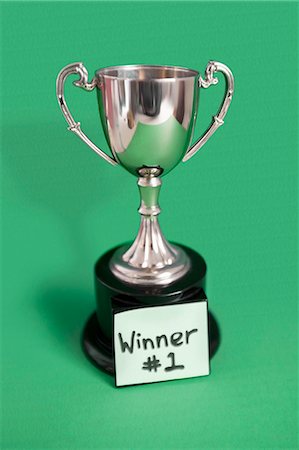 Trophy with sticky note for winner over colored background Stock Photo - Premium Royalty-Free, Code: 693-06325254