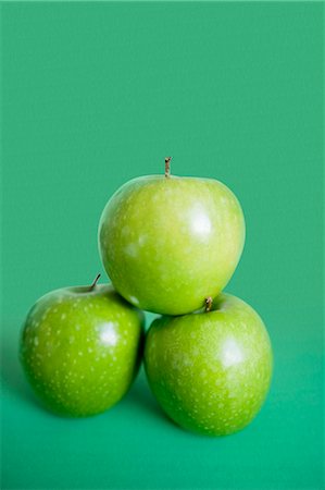 simsearch:693-06325158,k - Close-up of green apples in pyramid stack over colored background Foto de stock - Royalty Free Premium, Número: 693-06325260