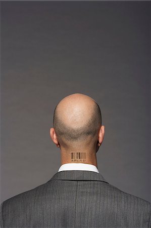 Bald headed businessman with barcode on his neck over gray background Fotografie stock - Premium Royalty-Free, Codice: 693-06325309